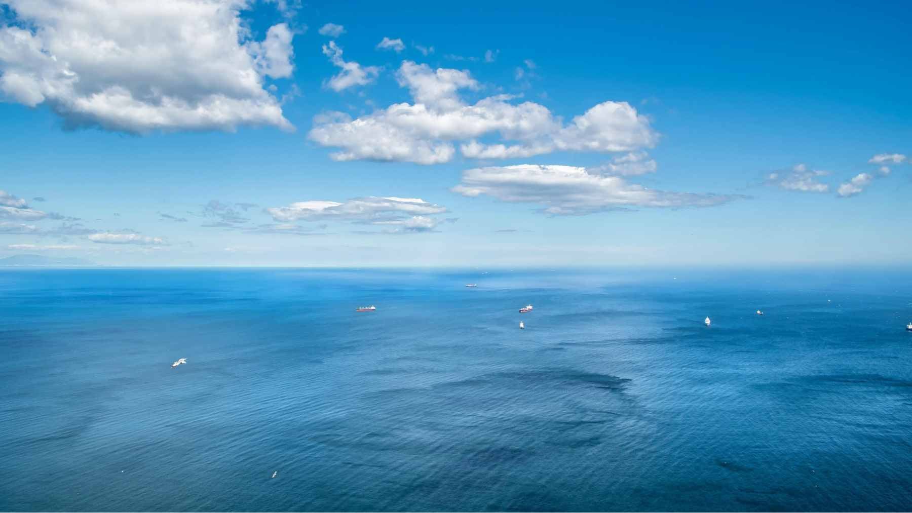 A conceptual illustration of specialized ships spraying fine seawater mist into the atmosphere to brighten marine clouds.