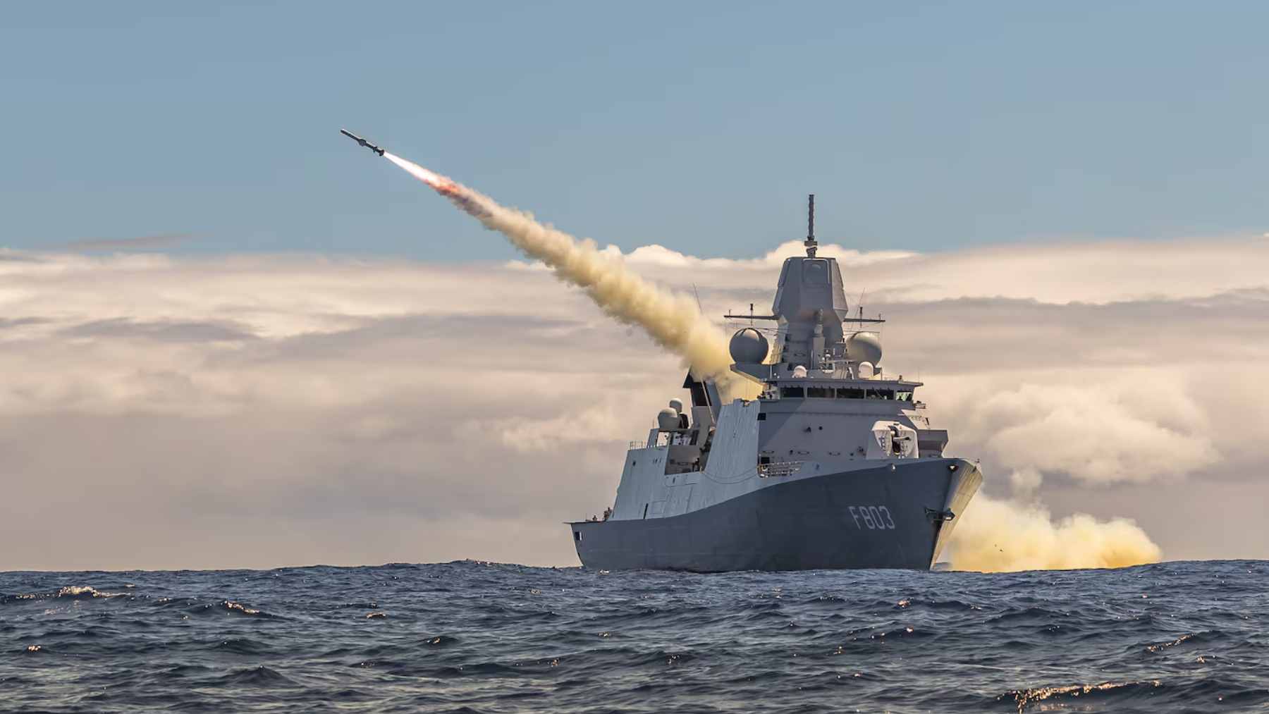 A high-angle view of a multinational naval fleet sailing in formation during RIMPAC maneuvers in the Pacific Ocean.