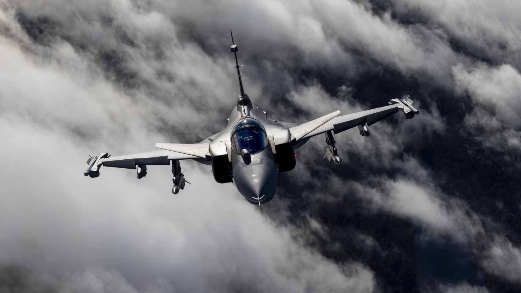 A Swedish Air Force JAS 39 Gripen fighter jet performing aerobatics with a visible smoke trail.
