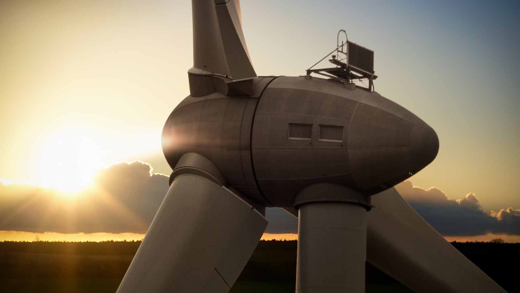 Massive wind turbines towering over a thriving cornfield in the rural Midwest, illustrating dual-use agricultural land.