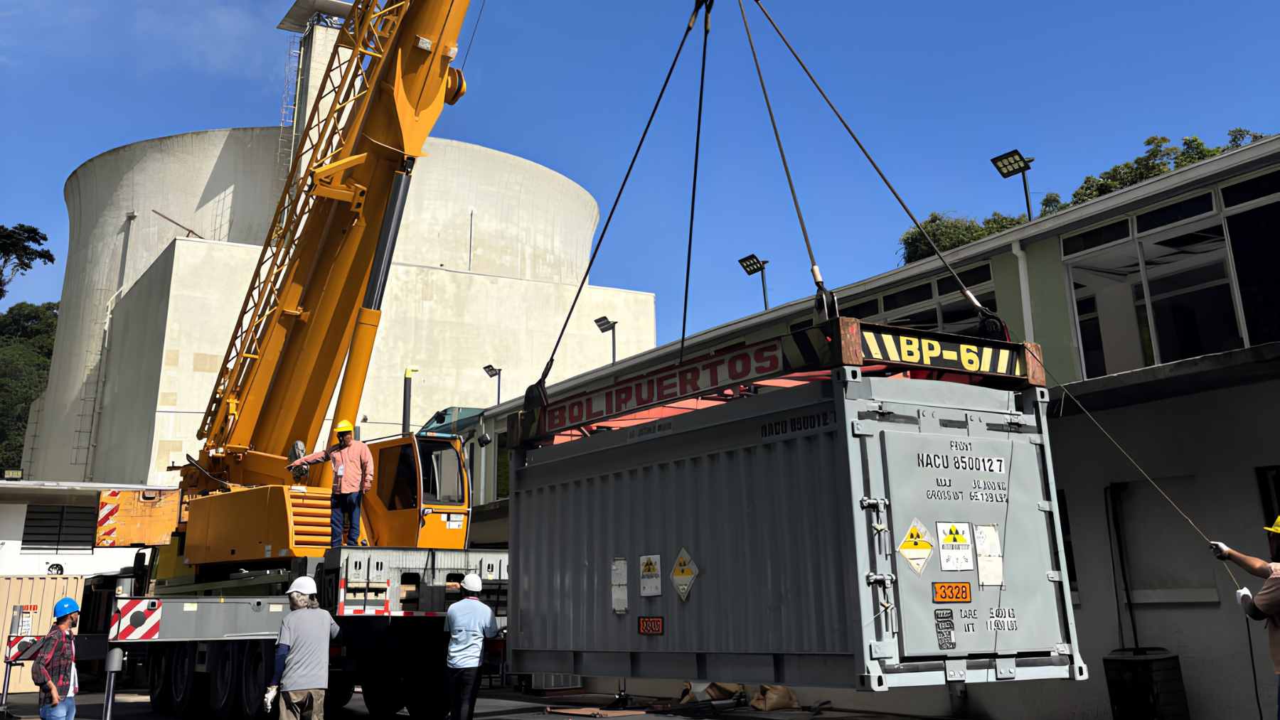 A heavy, secure nuclear spent fuel cask being monitored during a high-stakes transport operation from Venezuela.