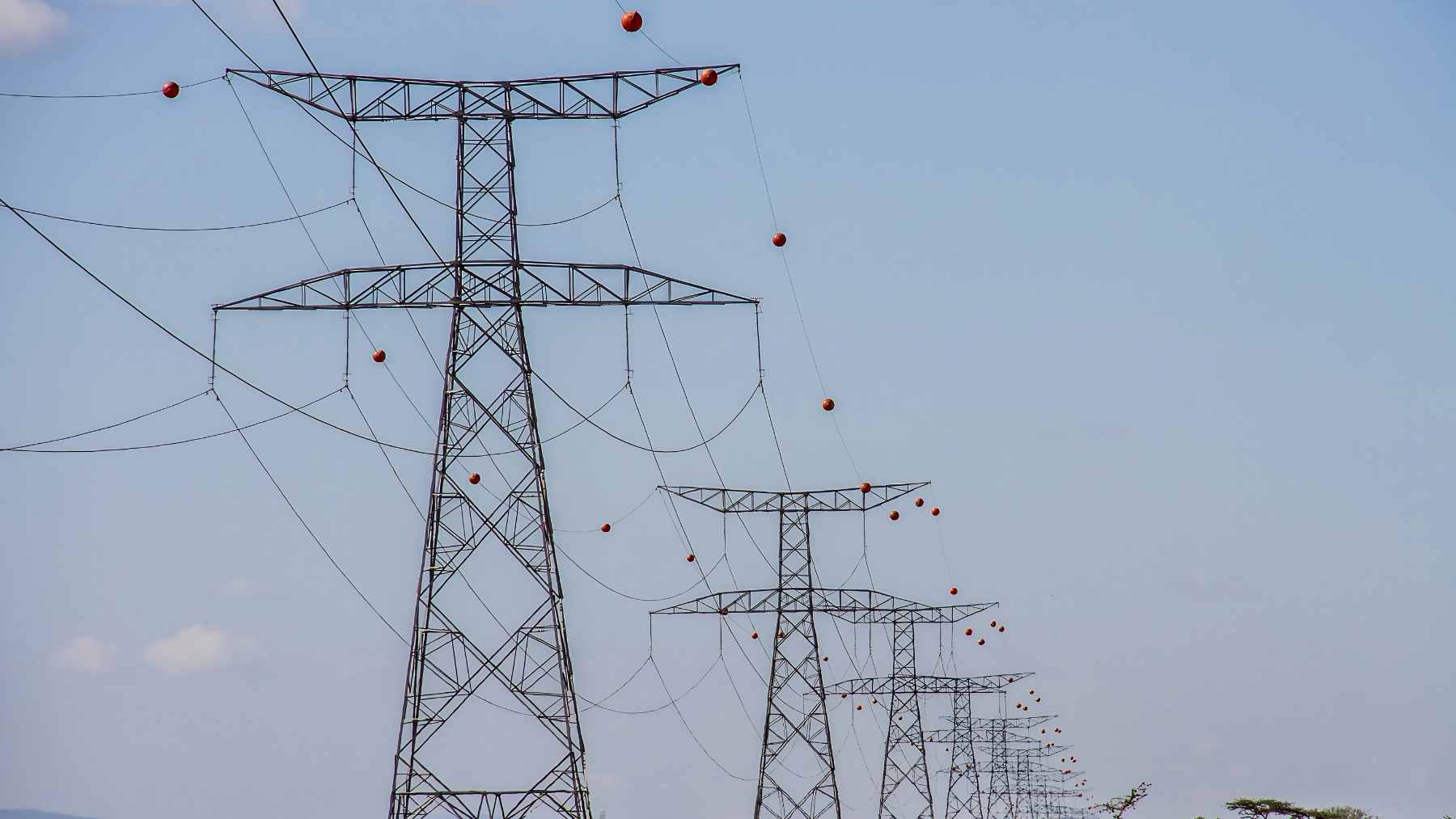 Bright aviation orange marker balls hanging from high-voltage transmission lines to increase visibility for low-flying aircraft.