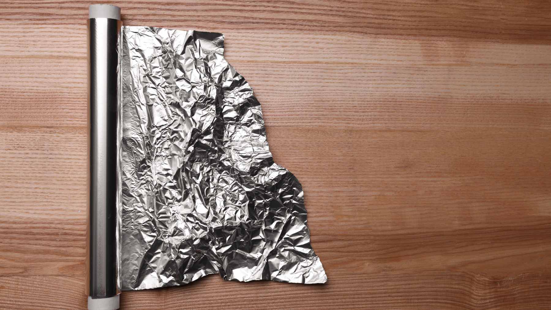 A close-up of a square of aluminum foil taped over a damp wall stain to test for moisture penetration.