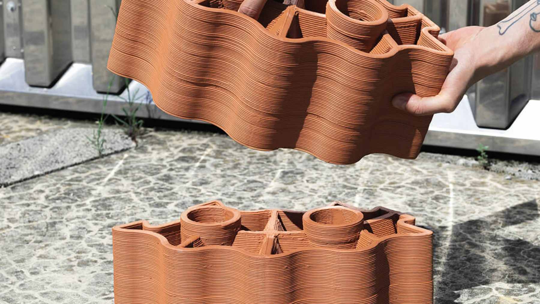 A modular 3D-printed terracotta brick system installed in an urban bus stop to provide natural evaporative cooling for commuters.