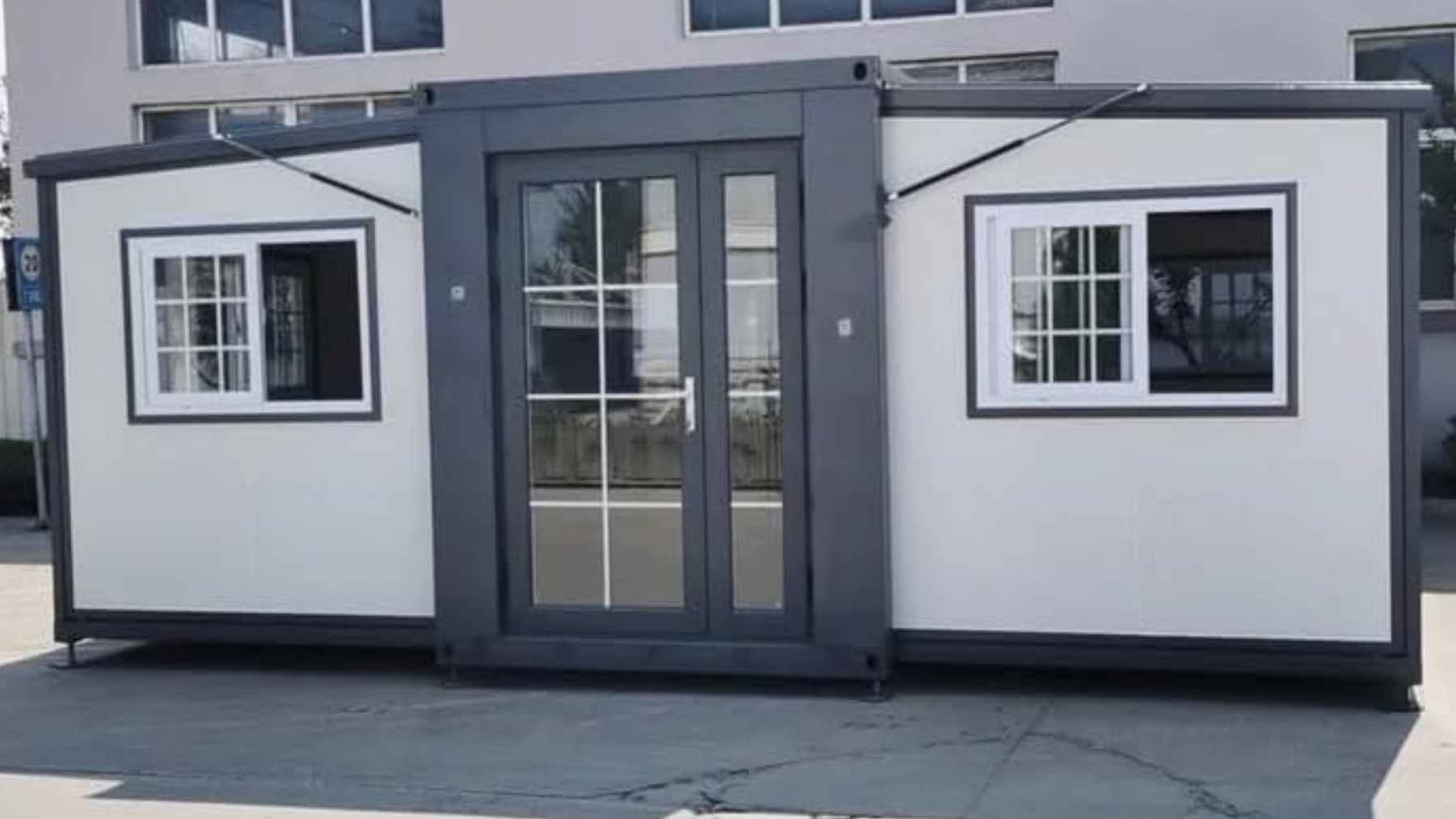 A sleek, foldable two-story modular steel container house being assembled on a residential plot.