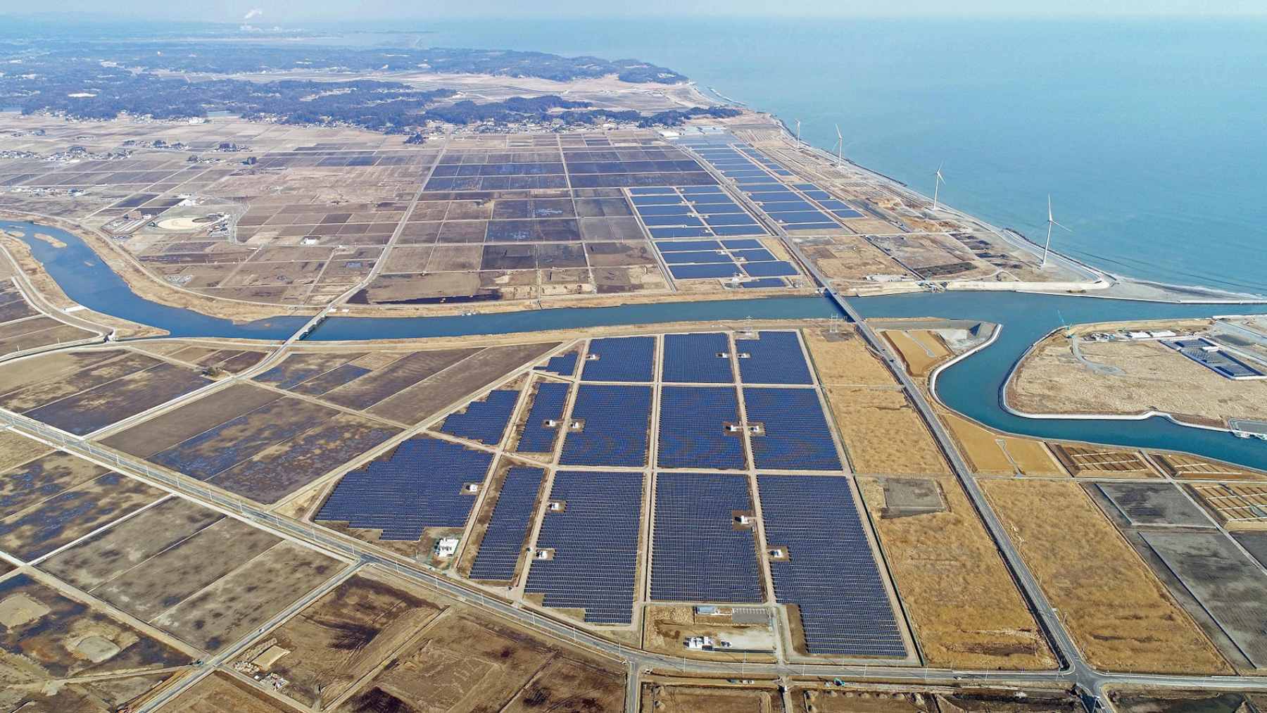 Aerial view of the Fukushima Sendatsuyama Solar Power Plant located on a mountainside, showing the massive expanse of photovoltaic panels.