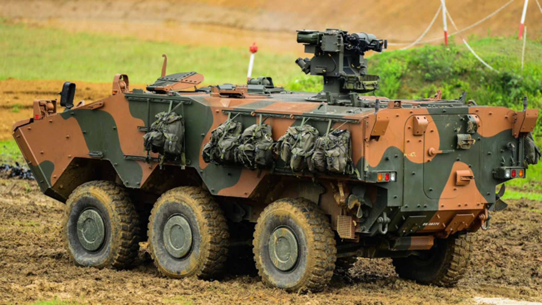A Brazilian Guarani 6x6 armored vehicle navigating through a flooded urban area during a disaster response operation.