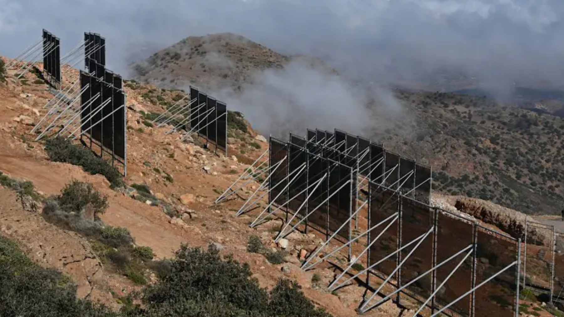 Fine mesh nets stretched across a mountain frame in Morocco, capturing water droplets from passing Atlantic fog.