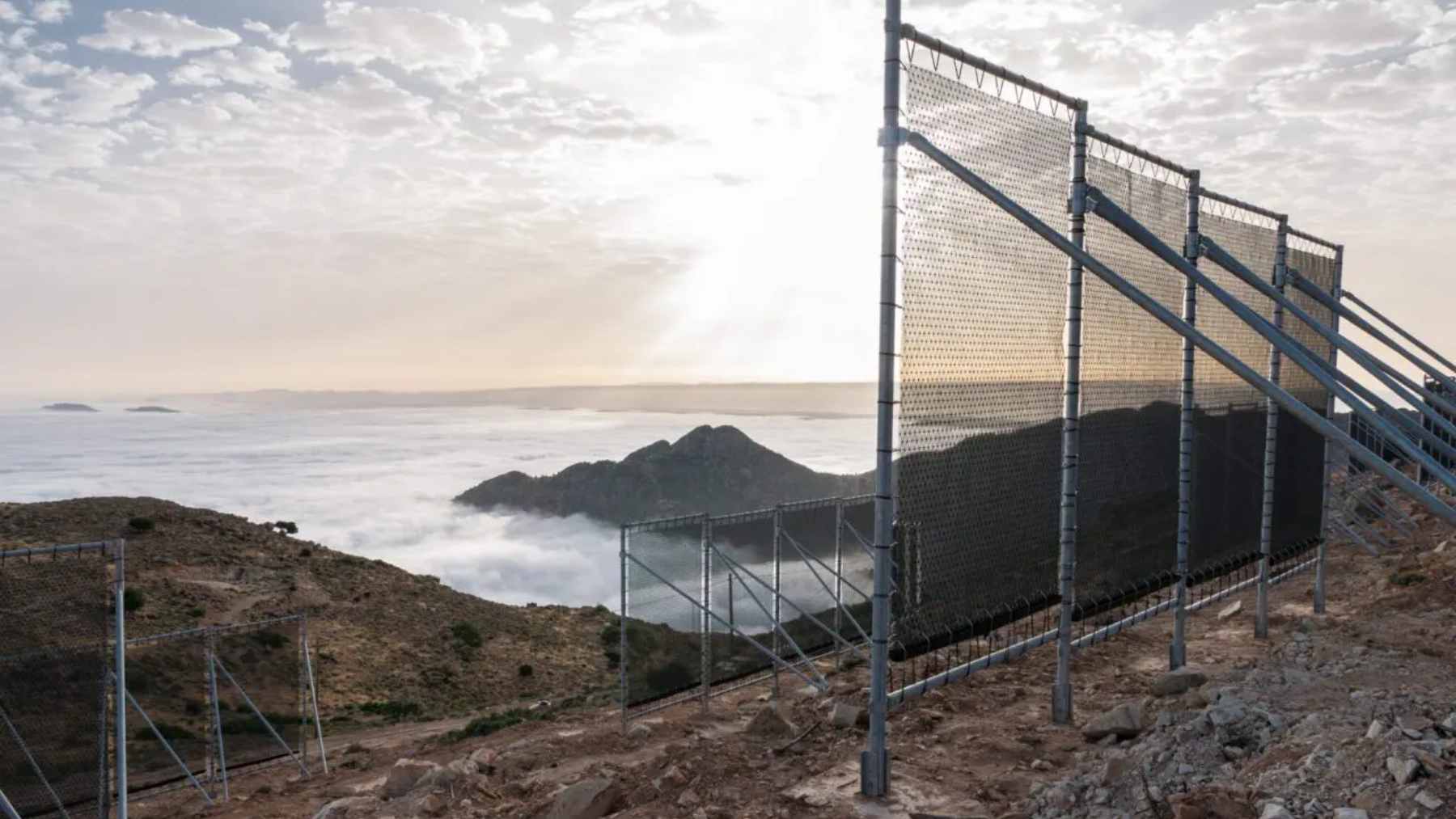 Fine mesh nets stretched across a mountain frame in Morocco, capturing water droplets from passing Atlantic fog.