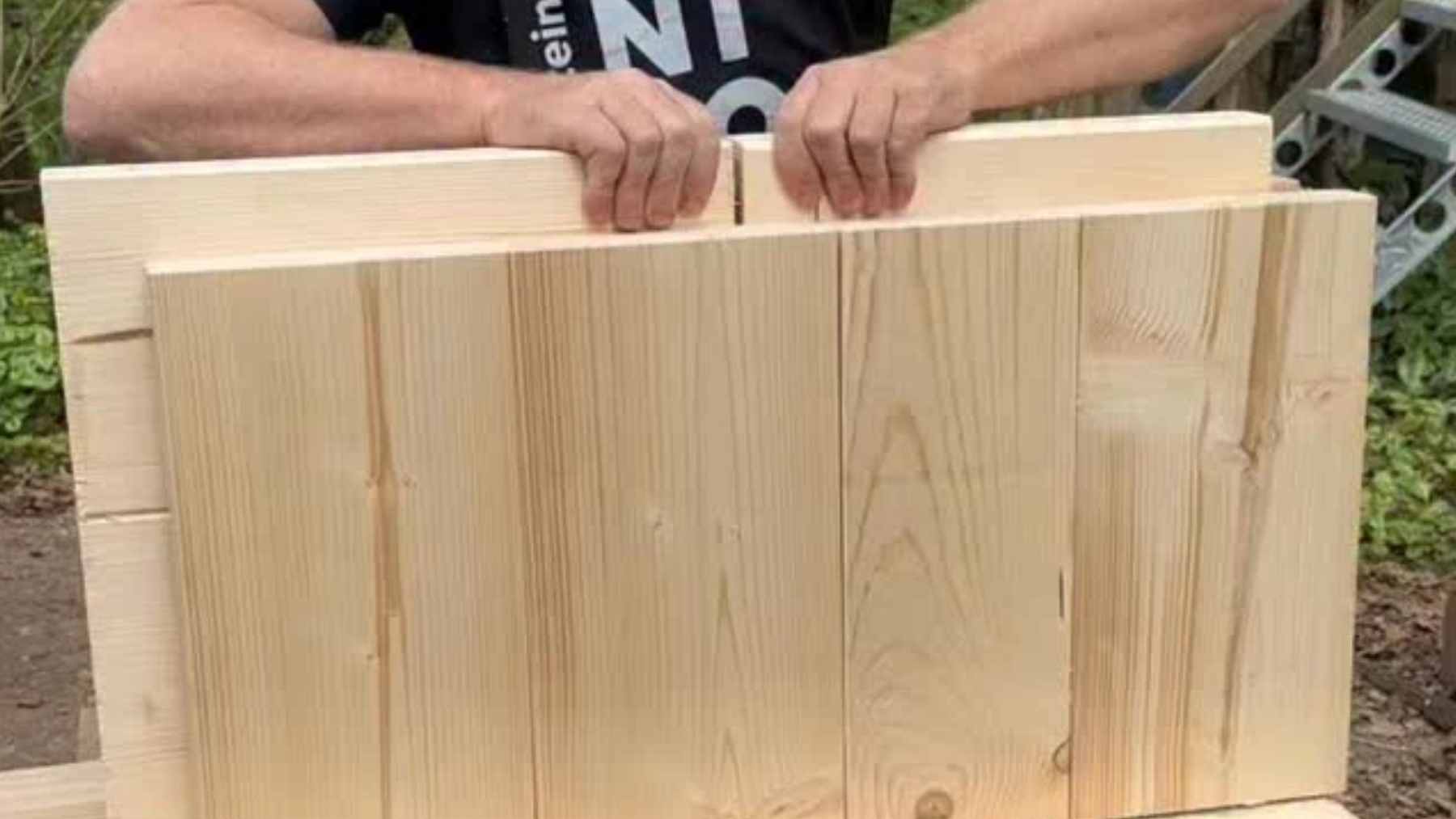 A construction crew assembling the structural walls of a house using large, interlocking solid-wood blocks that require no mortar or glue.