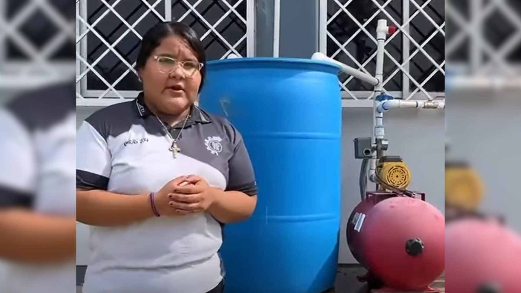A student demonstrating a hydroponic garden system that collects and treats condensation from an air conditioning unit to water plants.