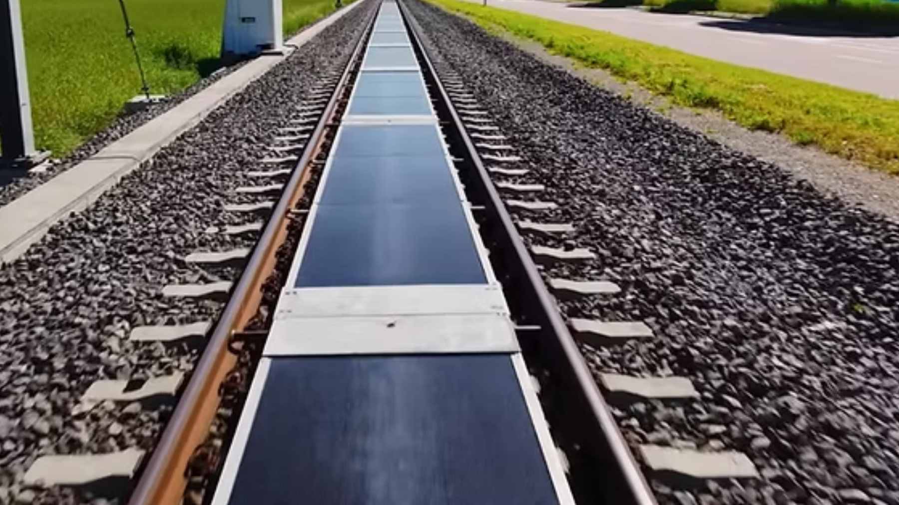 A section of an active Swiss railway track featuring removable solar panels installed between the steel rails to generate clean electricity.