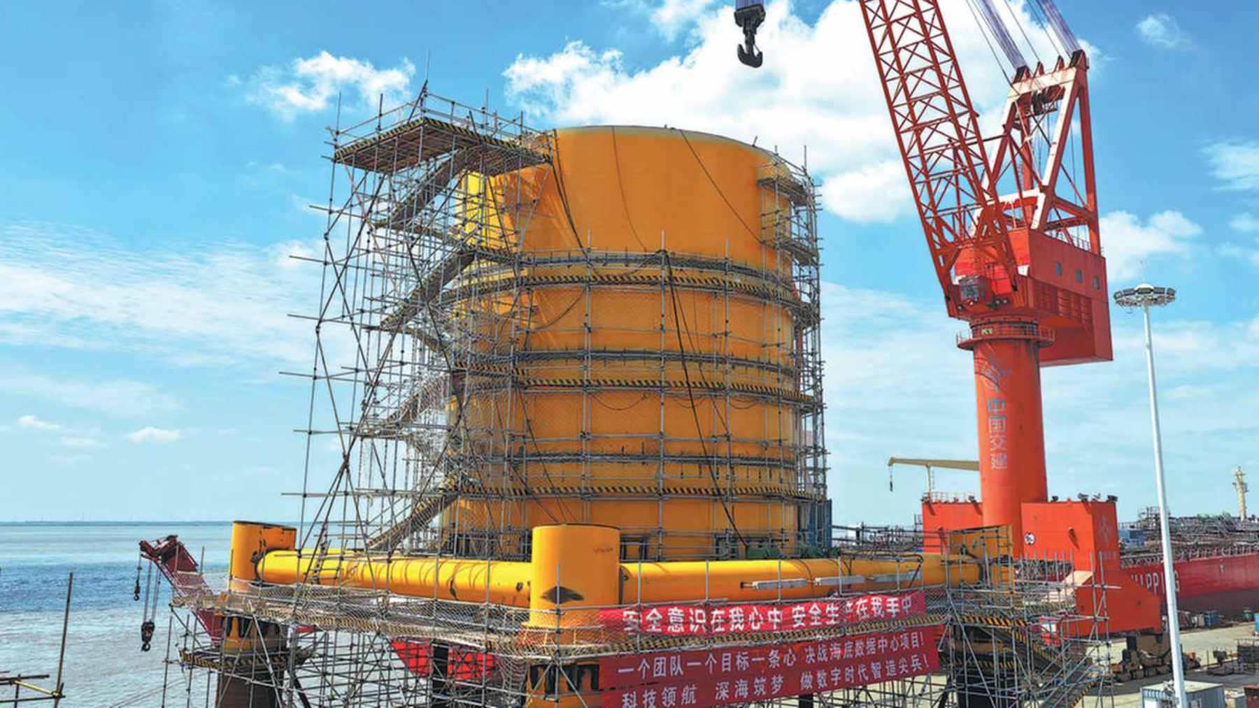 An offshore subsea data center module being submerged off the coast of Shanghai, integrated with nearby wind power infrastructure.
