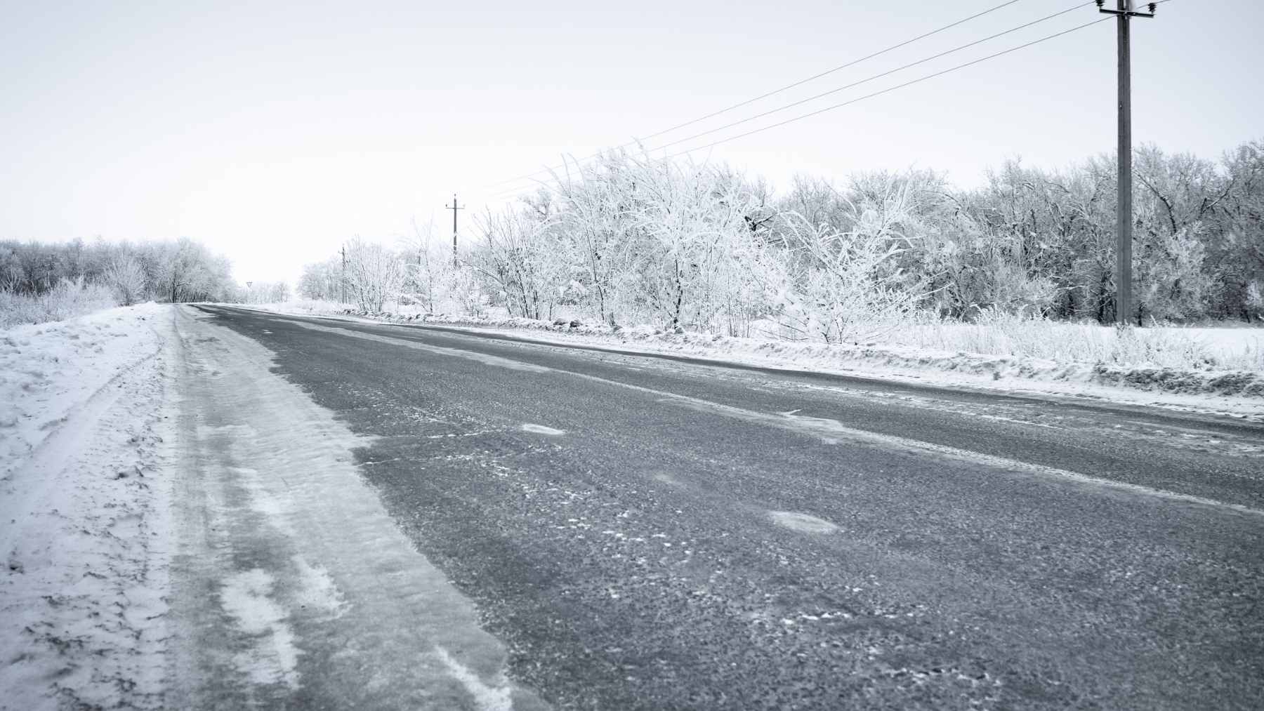 A municipal snowplow spraying a road with a tinted liquid mixture of brine and beet juice as an alternative to traditional rock salt.