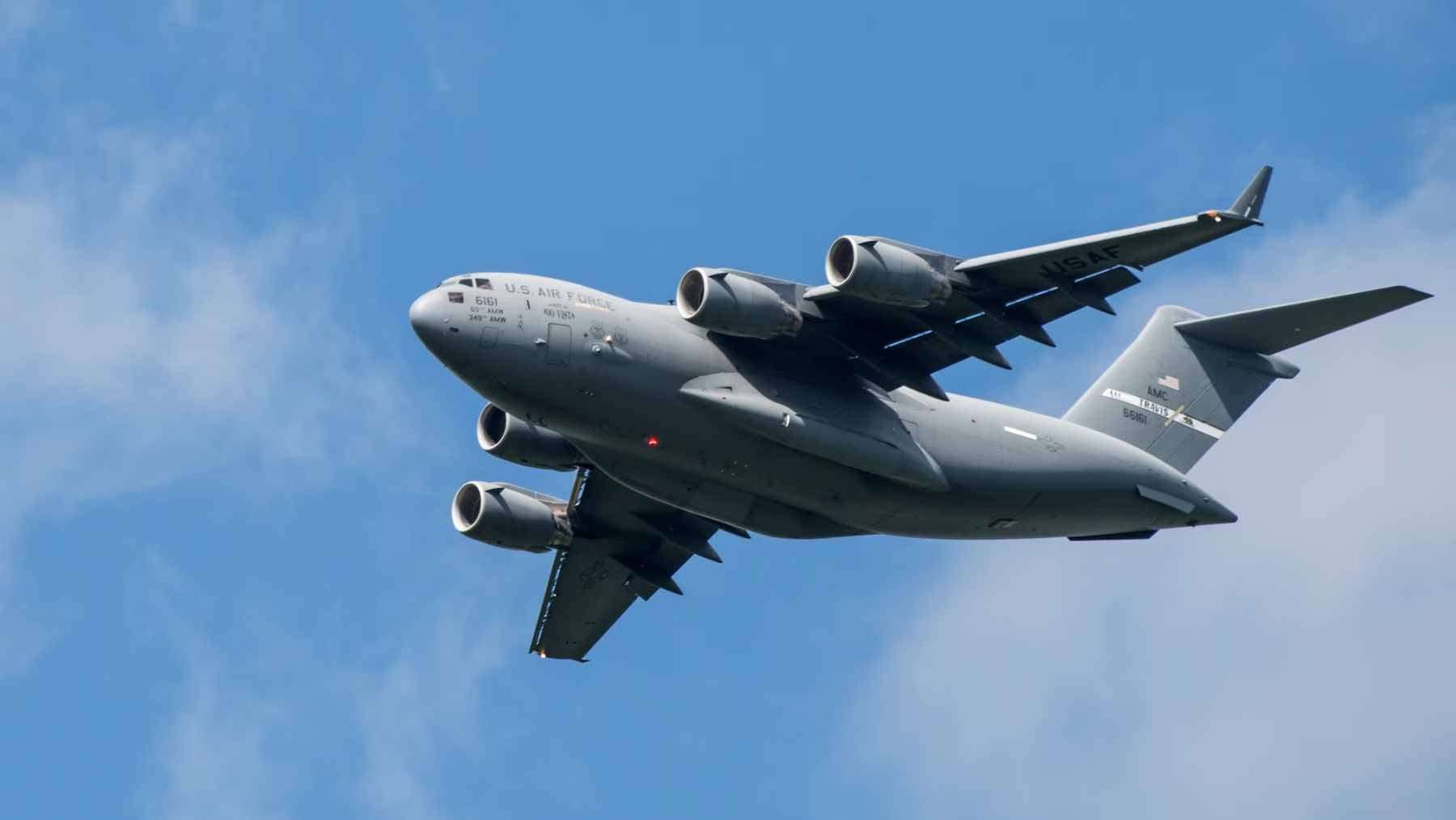 A Boeing C-17 Globemaster III performing a low-altitude landing with its externally blown flaps and engine exhaust streams clearly visible.