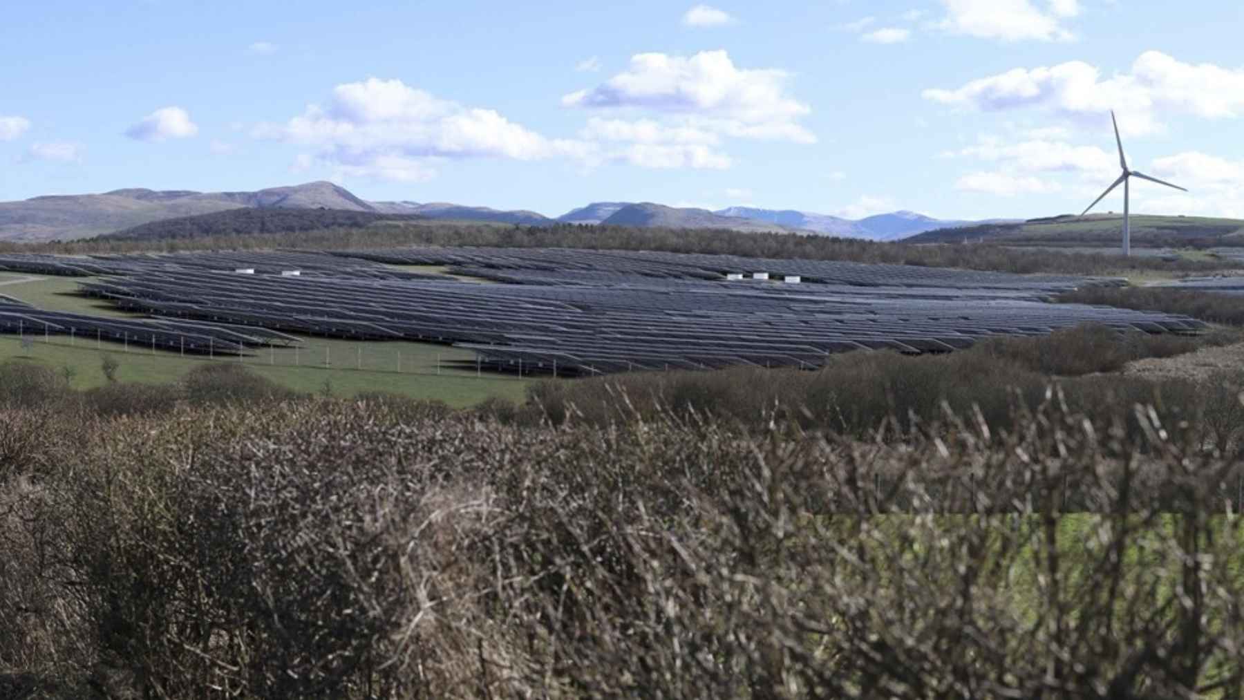 Rows of utility-scale solar photovoltaic panels installed across a green Cumbrian field, highlighting renewable energy development in the UK.