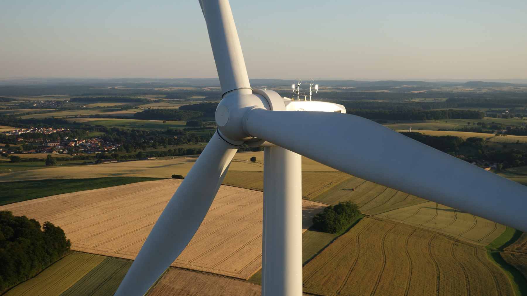 Modern utility-scale wind turbines installed in a rural agricultural landscape, representing renewable energy expansion.