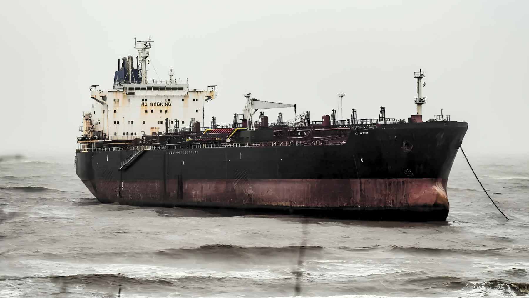 An abandoned oil tanker grounded on a rocky shoreline near Mumbai during monsoon season.