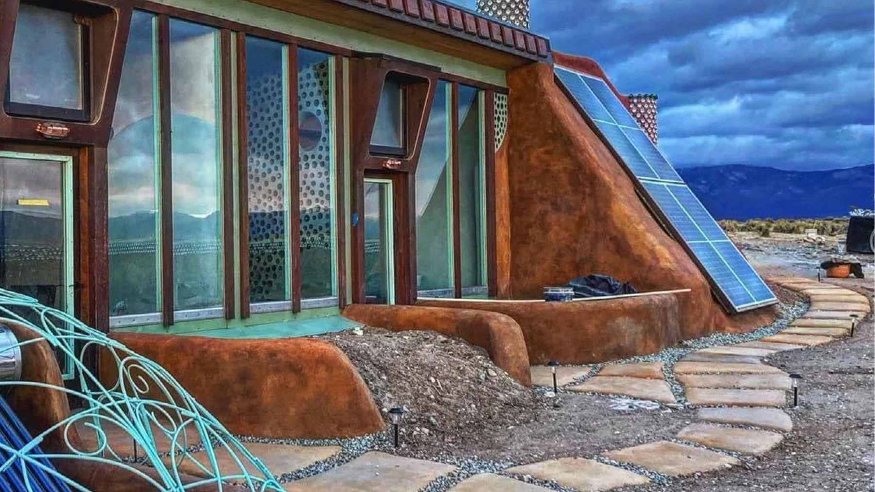 A New Mexico community built 100 homes into the earth with no power bills or water lines, and the pool they dug became something none expected 1 A natural swimming pond surrounded by desert landscaping in a New Mexico Earthship community, featuring native plants for water filtration.
