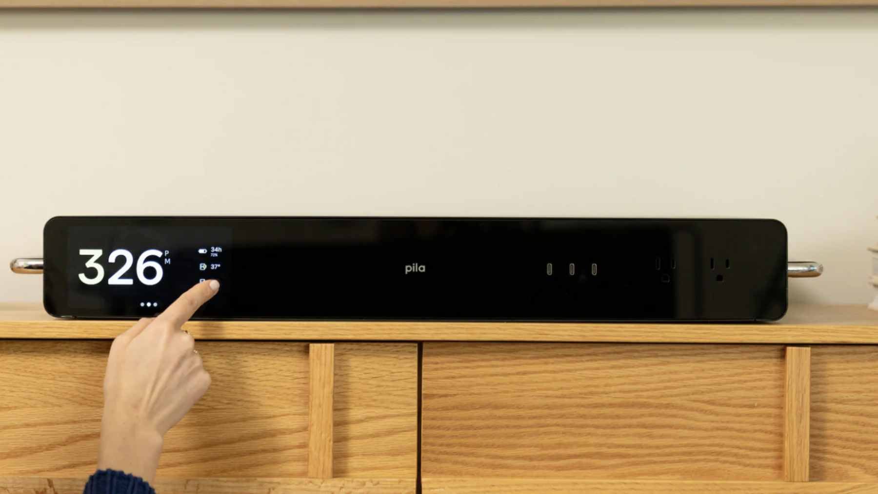 A sleek Pila Mesh Home Battery plugged into a standard residential outlet, showing its compact design compared to bulky traditional wall-mounted battery systems.