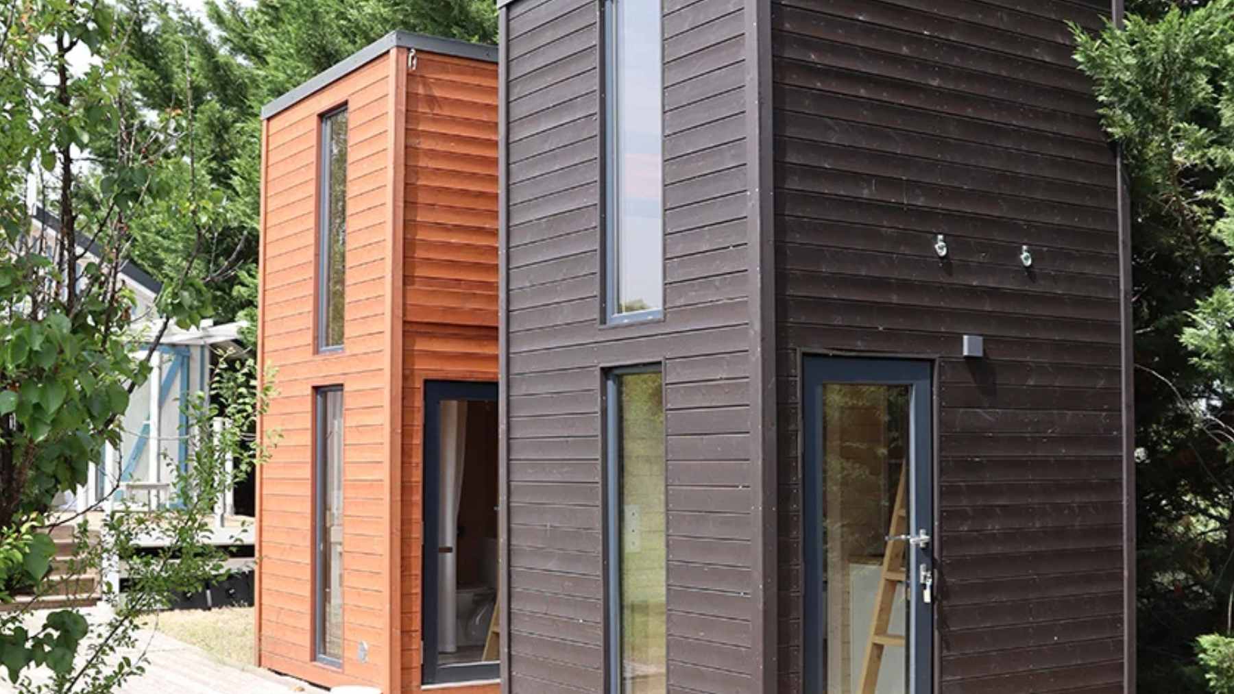 A vertical view of the La Ruche tiny house, showing its compact, two-story wooden design intended for garden studio use.