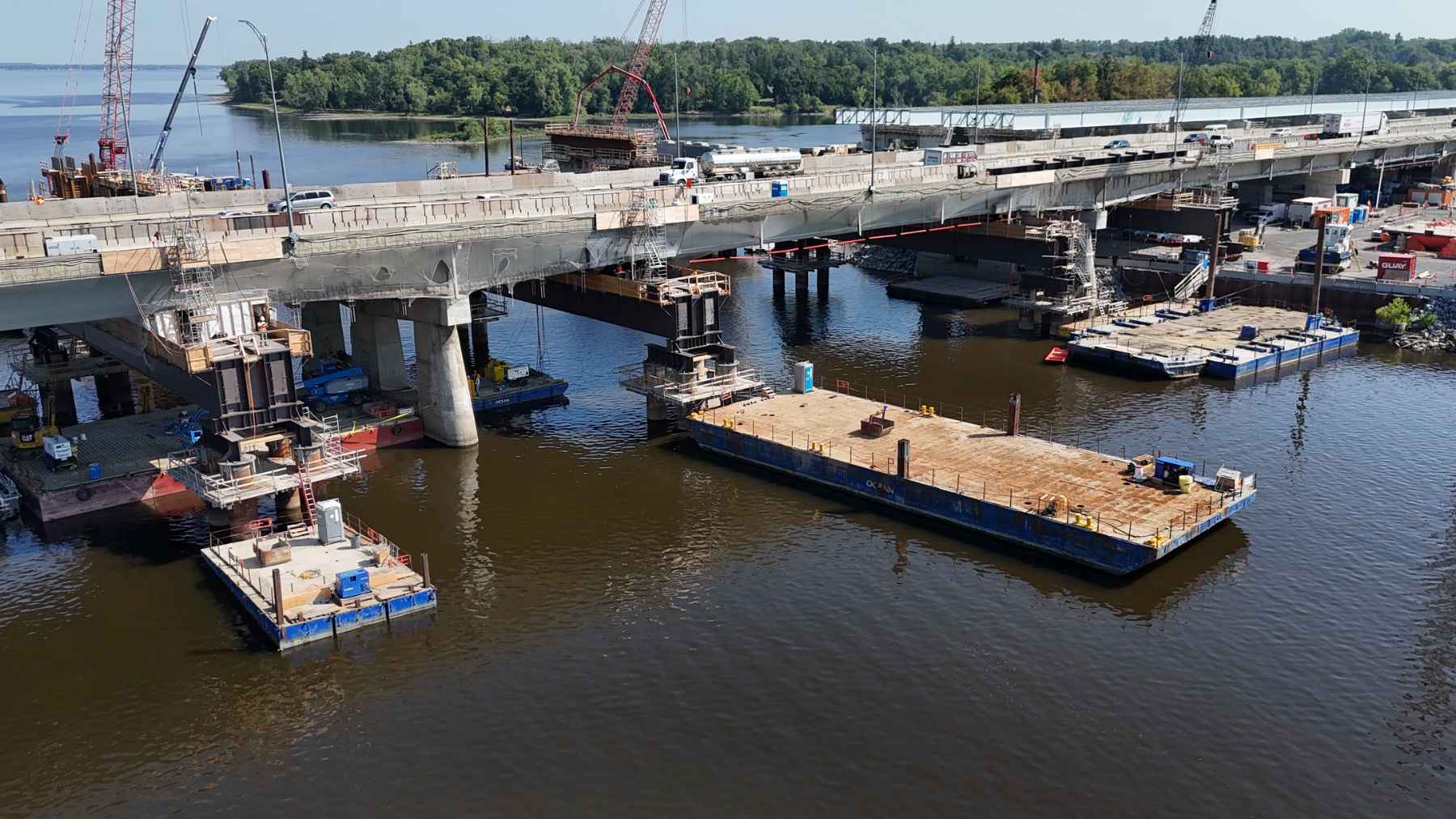 Construction work and concrete piers of the new Île-aux-Tourtes Bridge project spanning across the water in Quebec.