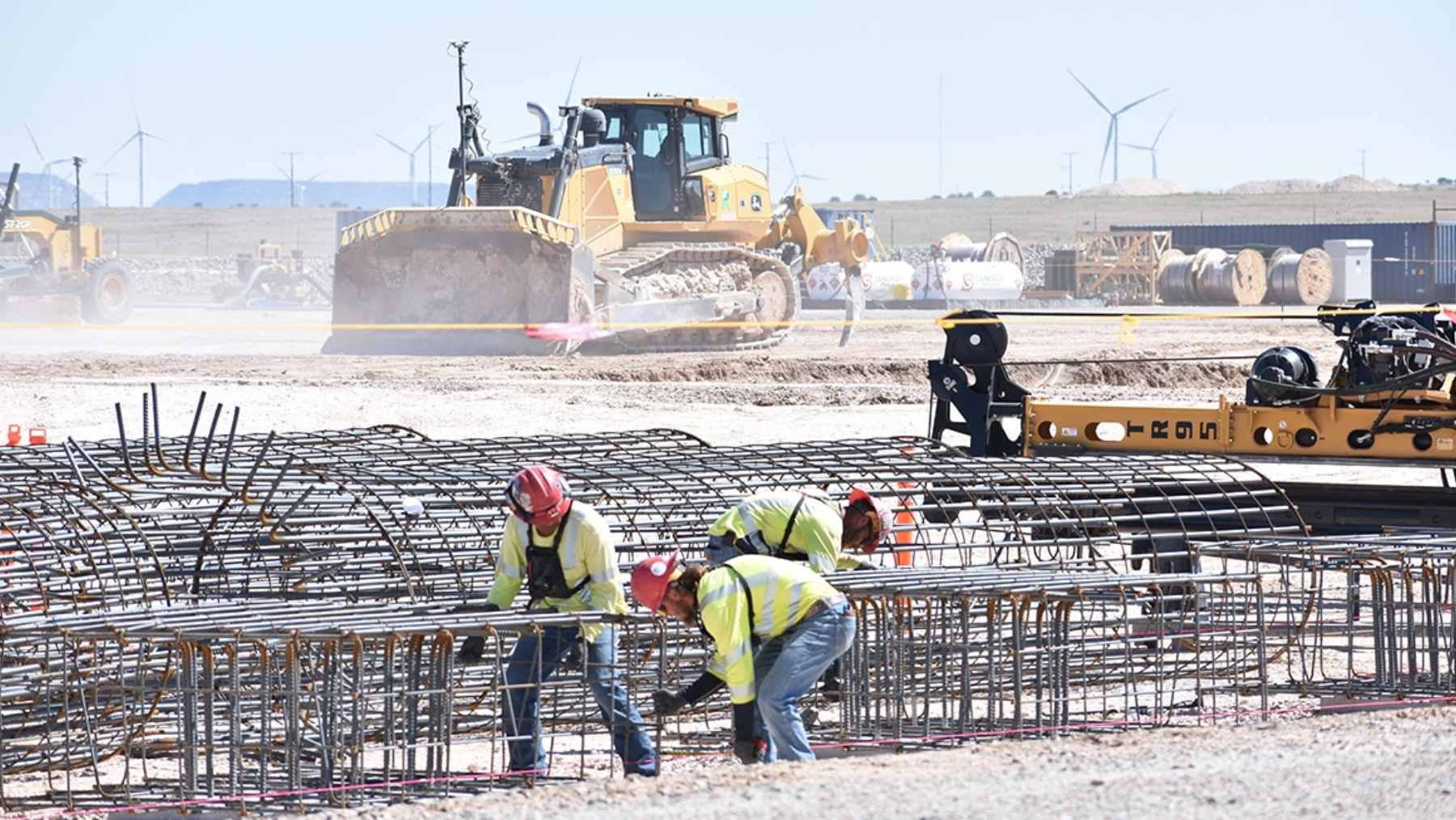 America just switched on its largest renewable project ever, and it now pumps out more power than the Hoover Dam 1 A massive wind farm landscape showing rows of turbines connected to high-voltage transmission lines in the New Mexico desert.