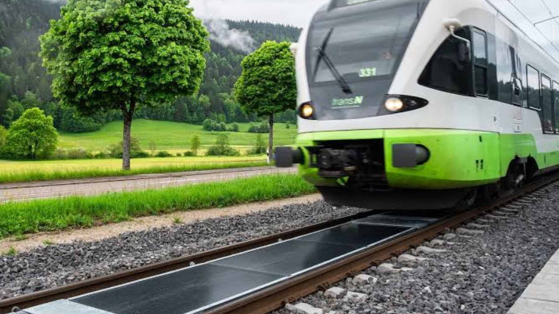 Photovoltaic solar panels installed between railway tracks in Switzerland, representing innovative renewable energy generation along active train lines.