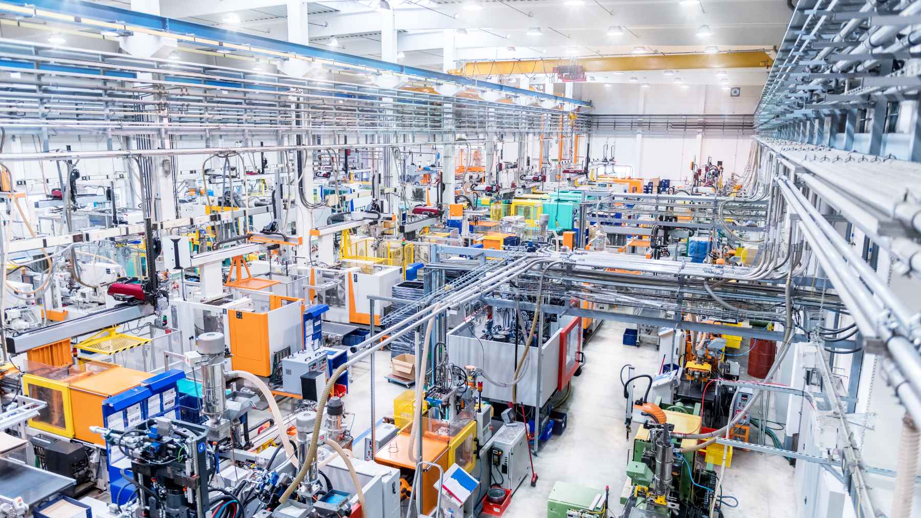 Workers and automated industrial technology operating inside an export manufacturing factory in Tijuana, Mexico.