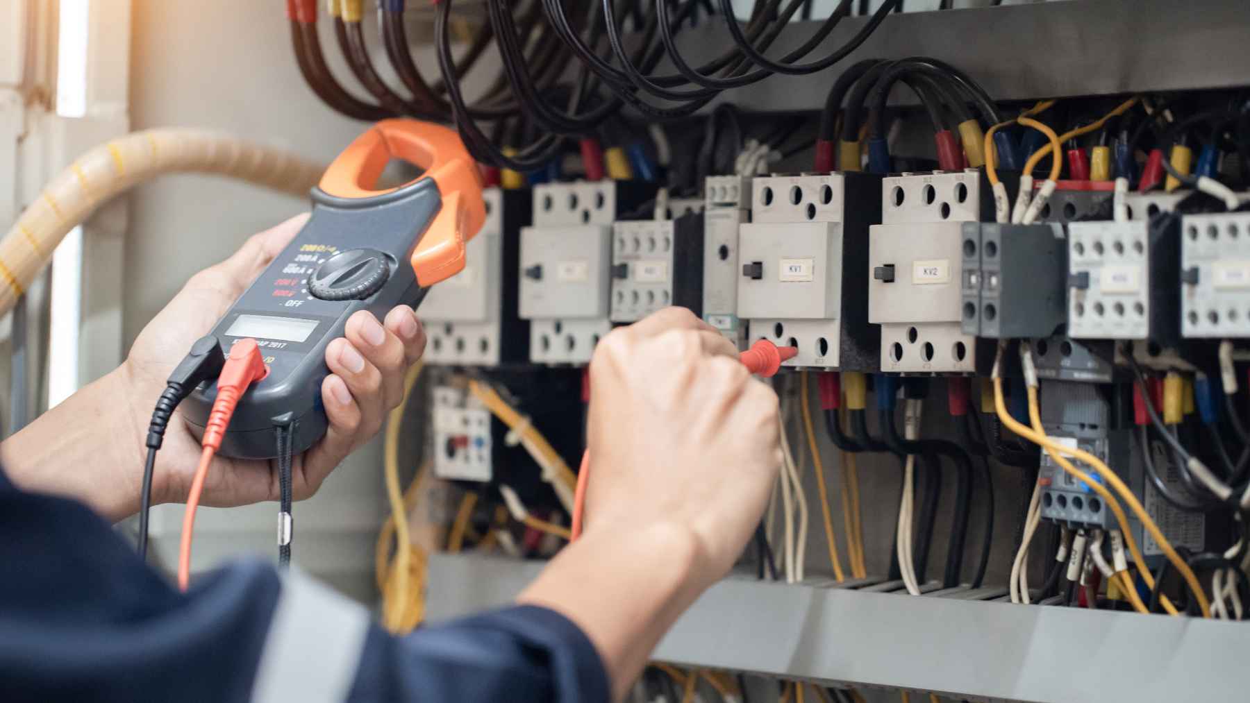 An experienced electrician working on wiring and electrical circuit components in a workshop.