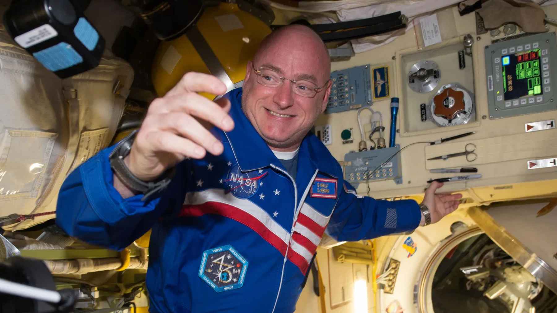 An astronaut floating inside the International Space Station looking out toward Earth's horizon.