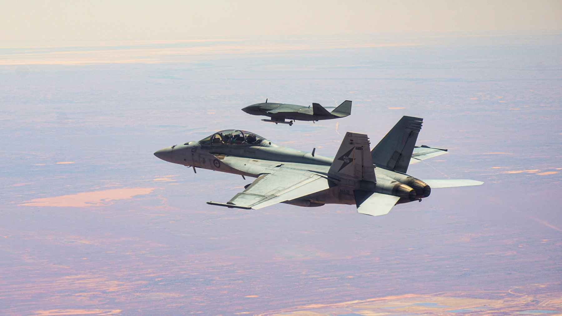 Boeing's MQ-28 Ghost Bat made its first appearance at Farnborough, and the jet it is built to escort 1 Boeing's MQ-28 Ghost Bat uncrewed tactical aircraft displayed on the tarmac at an international airshow.