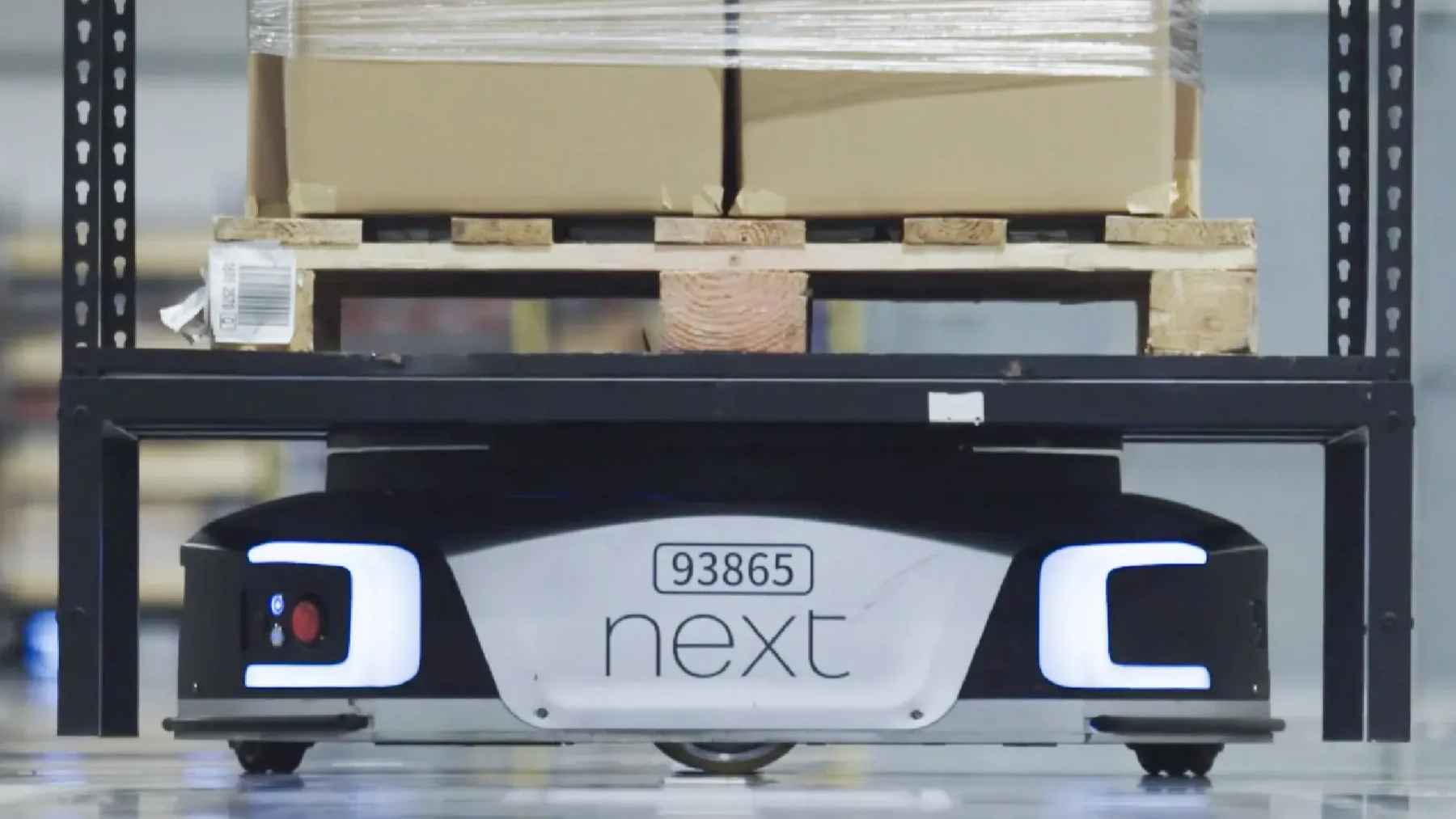 A Chinese robot army is now moving into UK supermarkets, filling a labor gap retailers can't close 2 Autonomous mobile robots operating inside a modern retail warehouse, representing supply chain automation and robotics.
