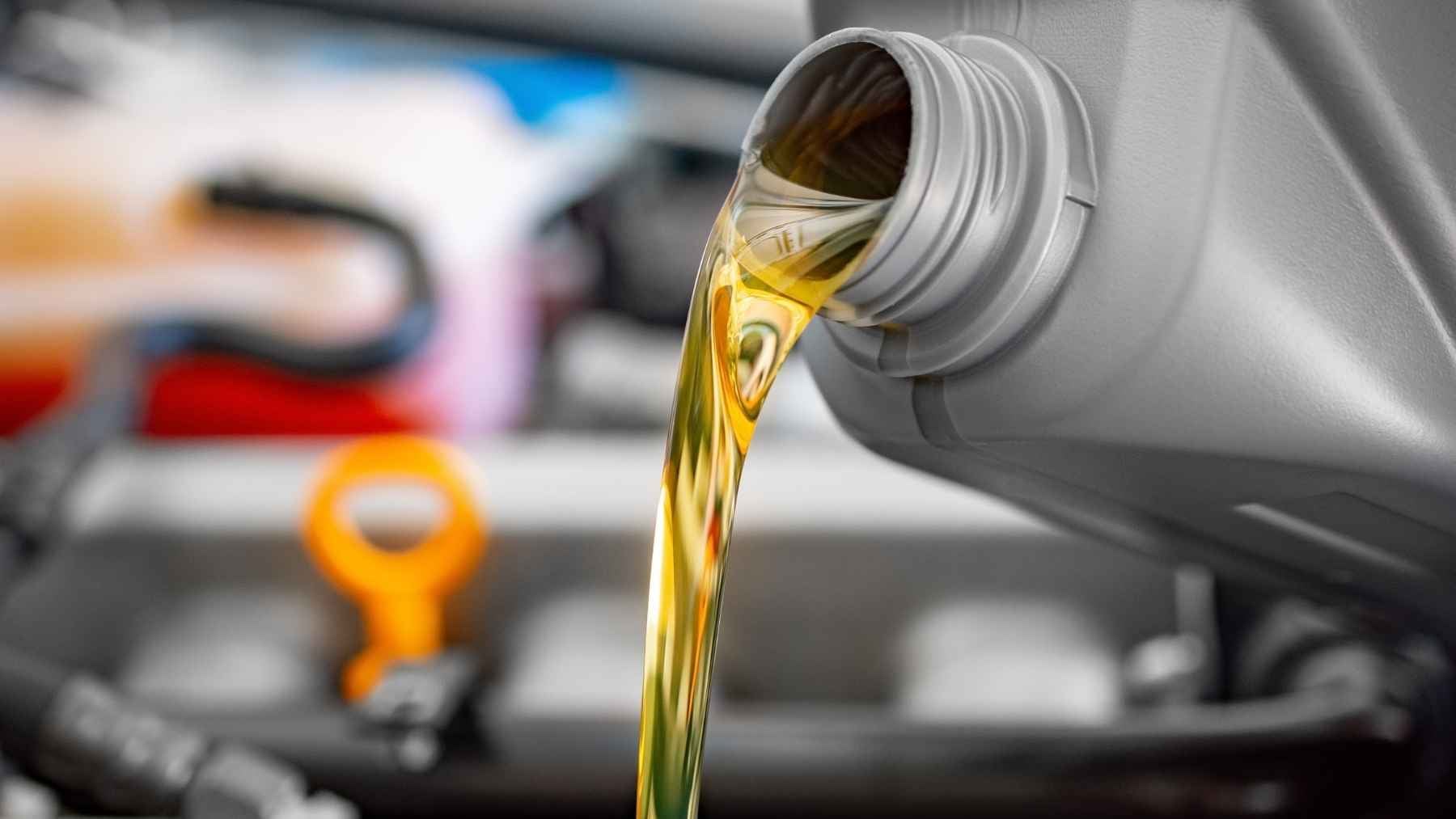 A mechanic pouring certified motor oil into a modern vehicle engine, emphasizing proper maintenance and viscosity grades.
