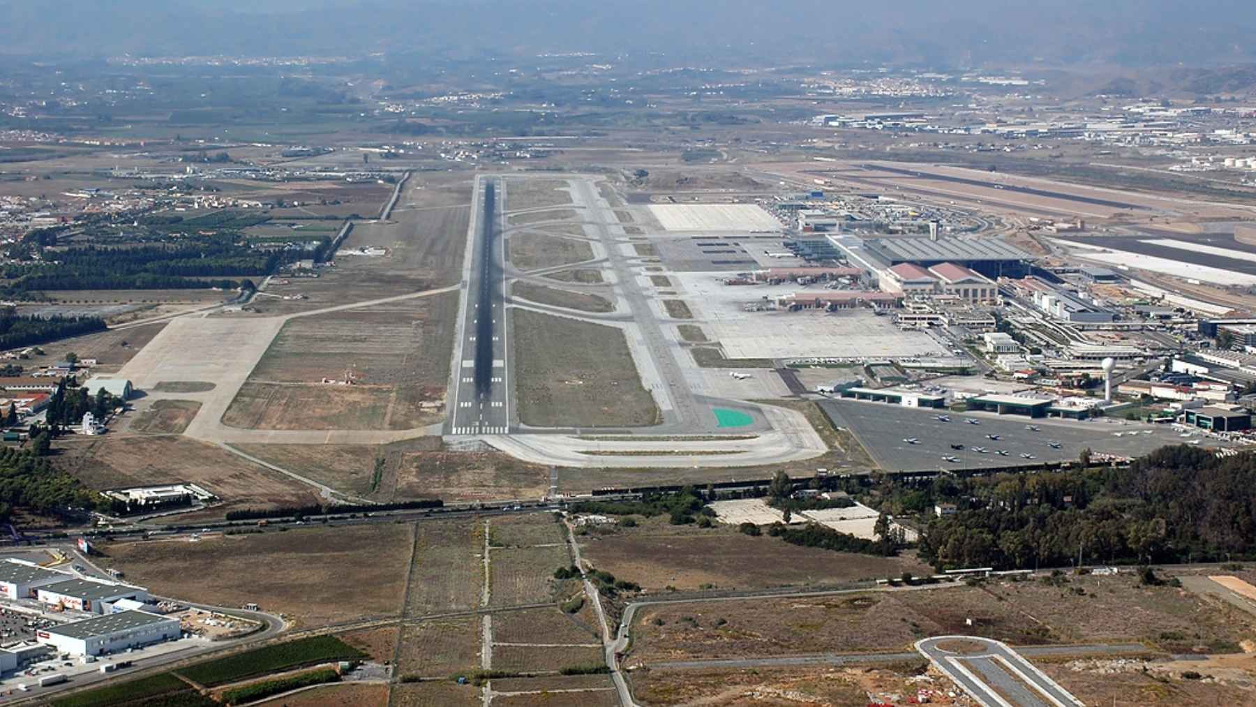 A 120-acre logistics park beside Málaga airport went back to square one after five years, because its environmental clearance expired first 2 An aerial view of commercial land and infrastructure near an airport, representing the stalled La Loma I logistics park project in Málaga, Spain.