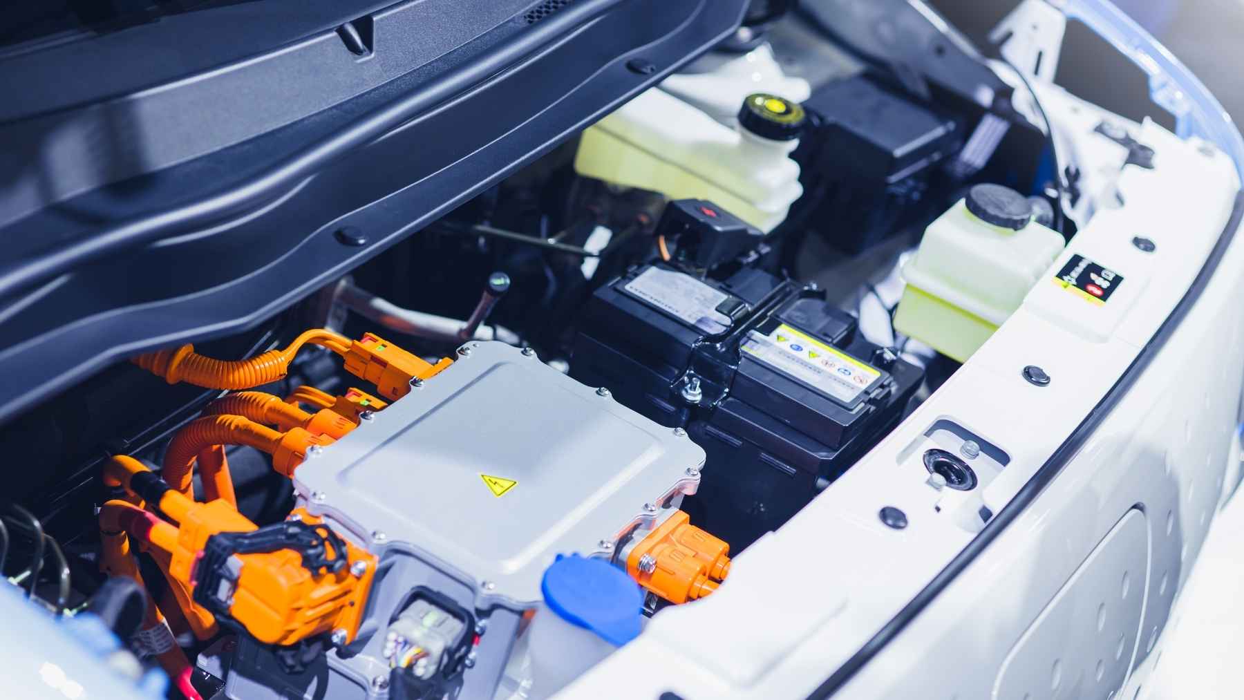 An independent mechanic inspecting engine components and spare parts of a modern Chinese vehicle in a workshop.