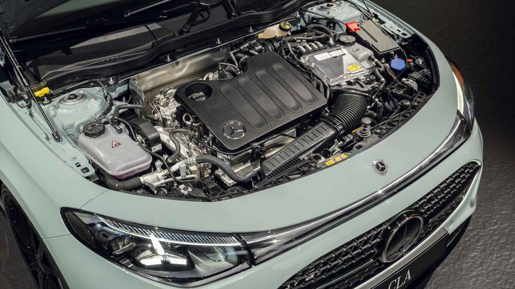 A modern hybrid engine under the hood of a luxury Mercedes vehicle, highlighting international powertrain manufacturing.
