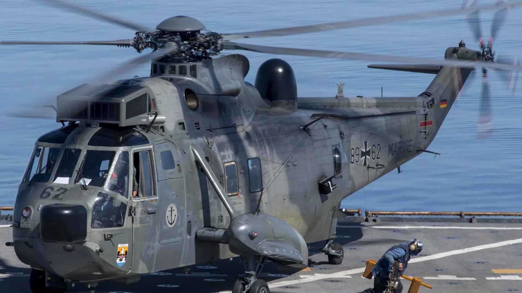 A Sea King helicopter equipped with rows of interceptor drones on launch rails at an airshow exhibition.