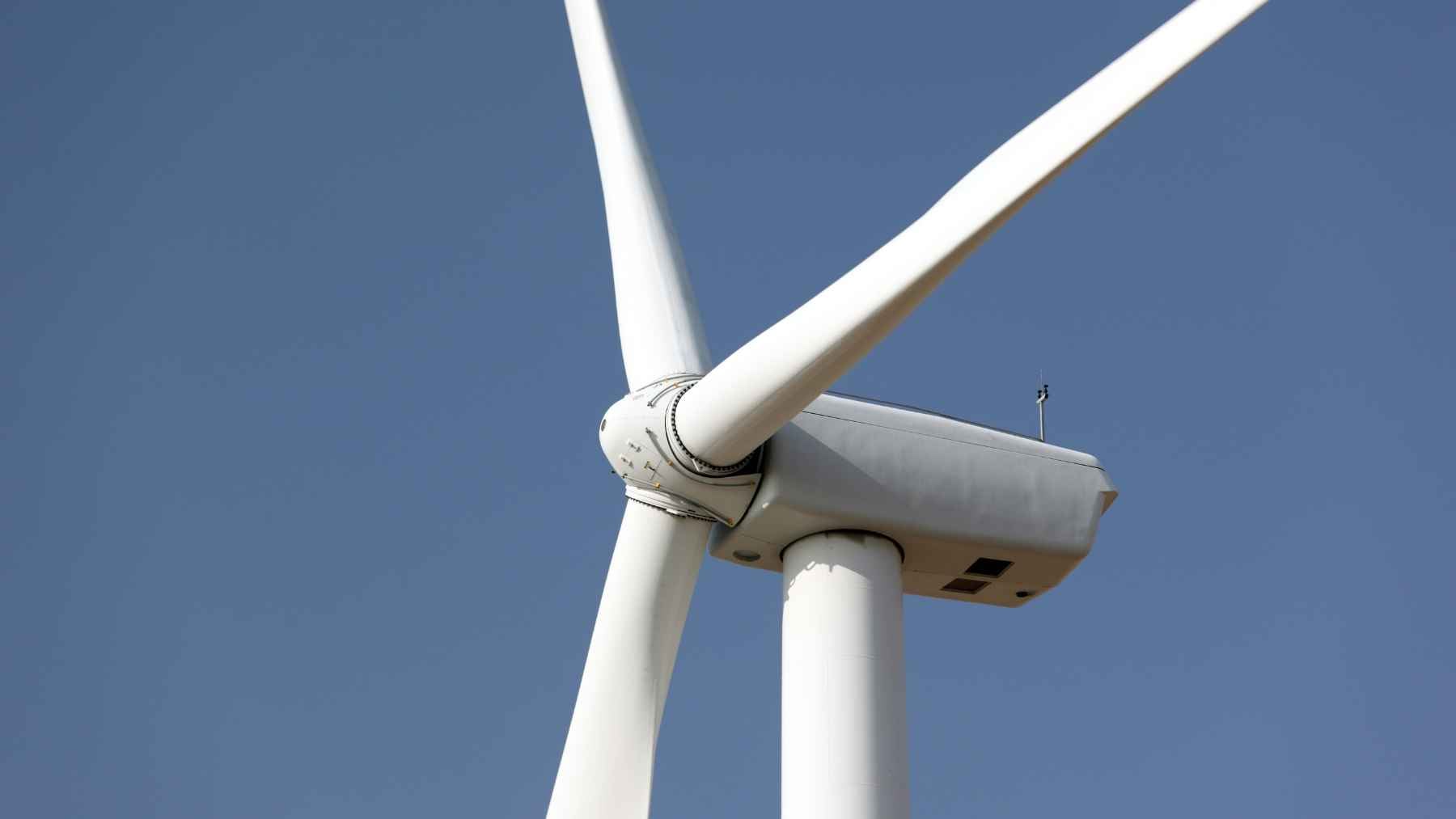 A discarded giant wind turbine blade laid out at a recycling and processing facility.
