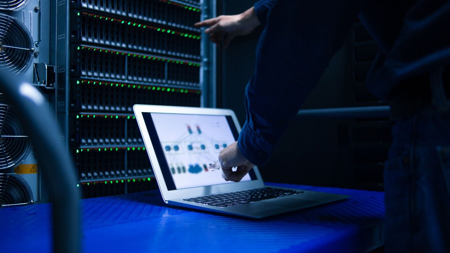 Servidores en un centro de datos mientras un técnico supervisa la red ante riesgos de ciberataques y brecha de ciberseguridad.