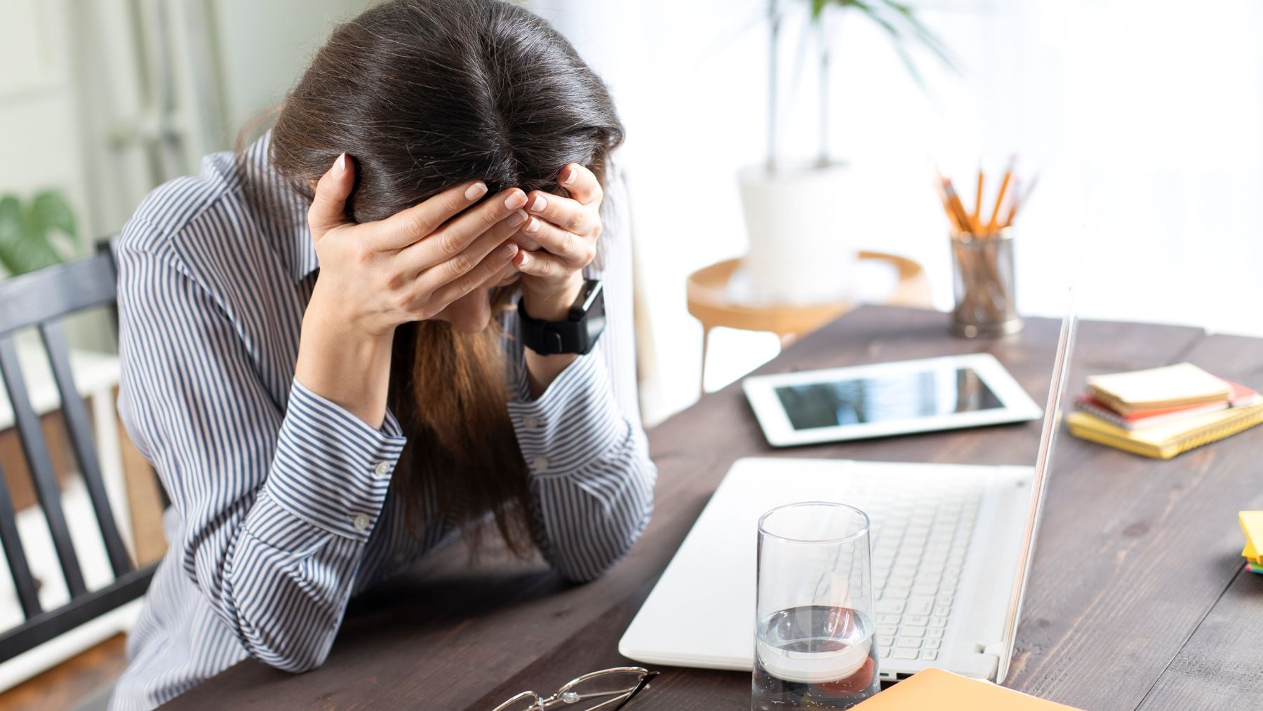 Mujer aparentemente desbordada en el trabajo frente al ordenador, imagen relacionada con apego evitativo e inhibición emocional.