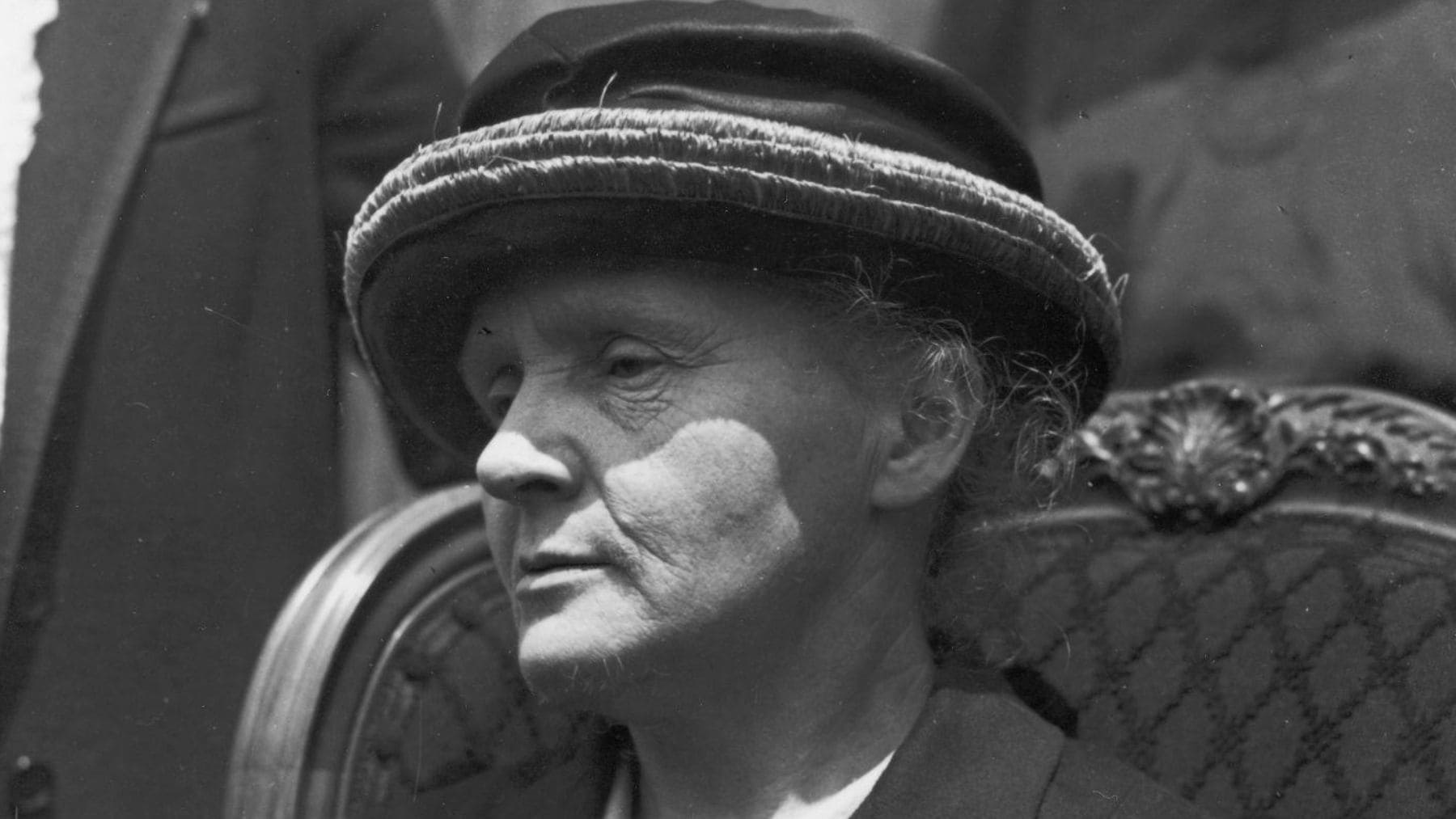 Marie Curie sentada en un acto público en una fotografía histórica en blanco y negro.