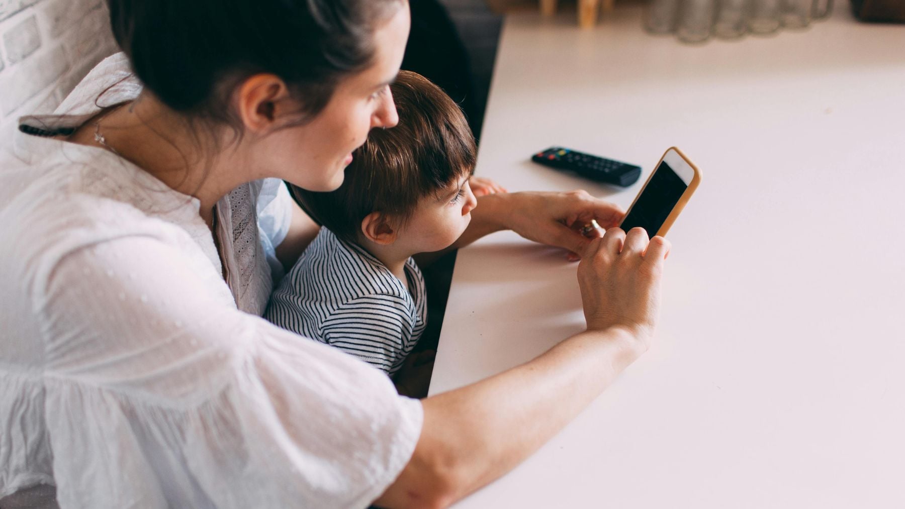 Madre y niño pequeño viendo vídeos en YouTube en un móvil, ejemplo del consumo infantil de contenido online.