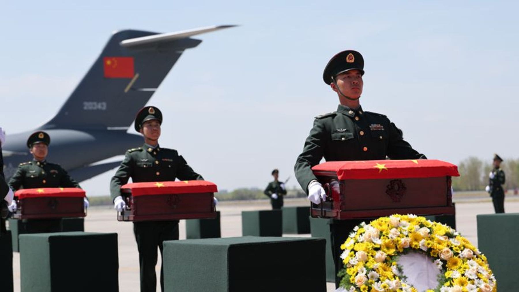 Soldados del Ejército chino trasladan ataúdes en un acto oficial con bandera en una base militar de China.