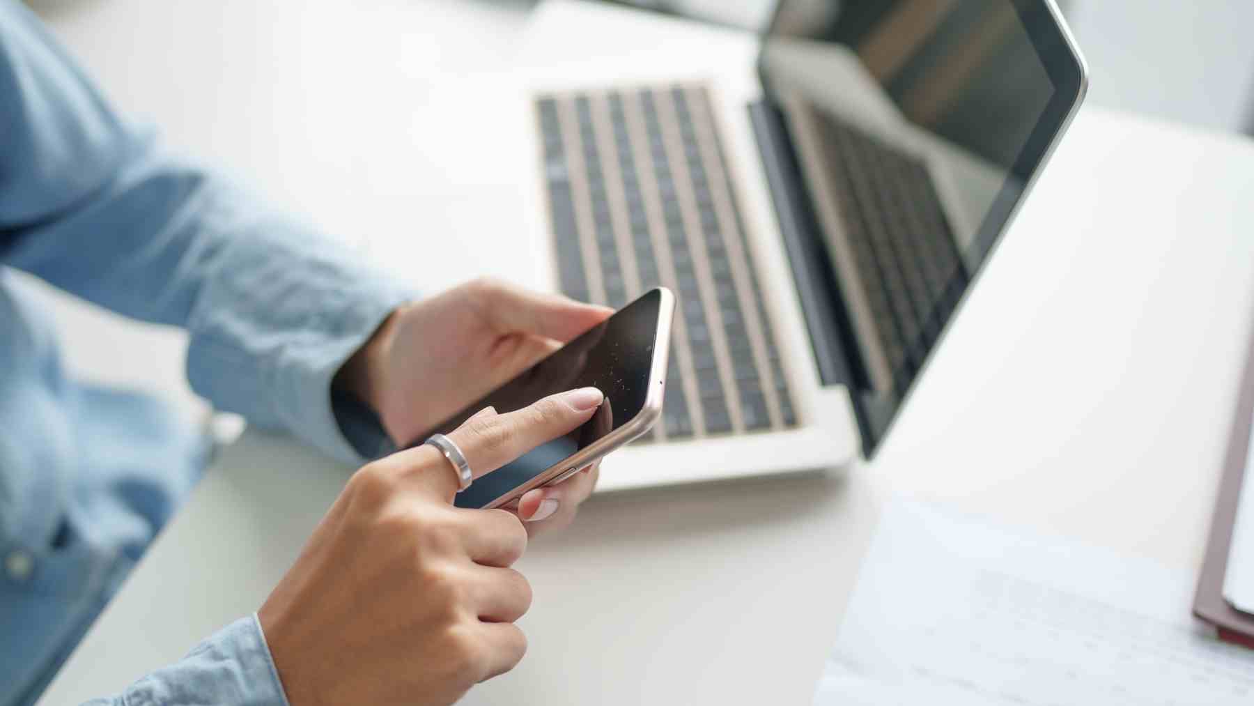 Persona usando movil para gestionar tarifa telefonica desde app en casa.