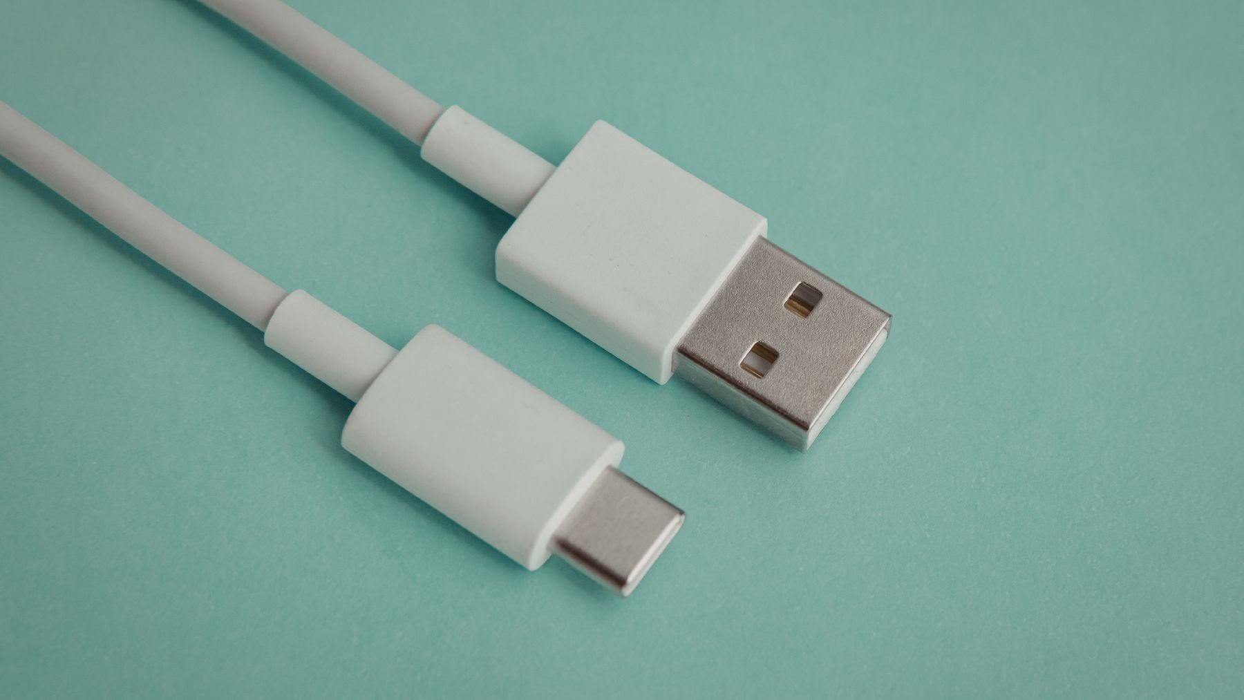 Cable USB-C junto a conector USB-A sobre fondo verde que representa el cambio de norma en cargadores de la UE.