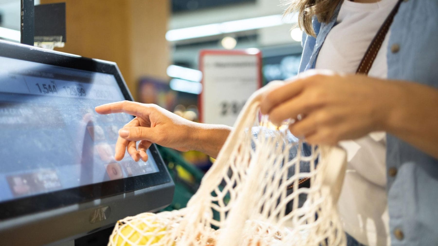 Cliente utilizando una caja de autopago en un supermercado mientras realiza la compra