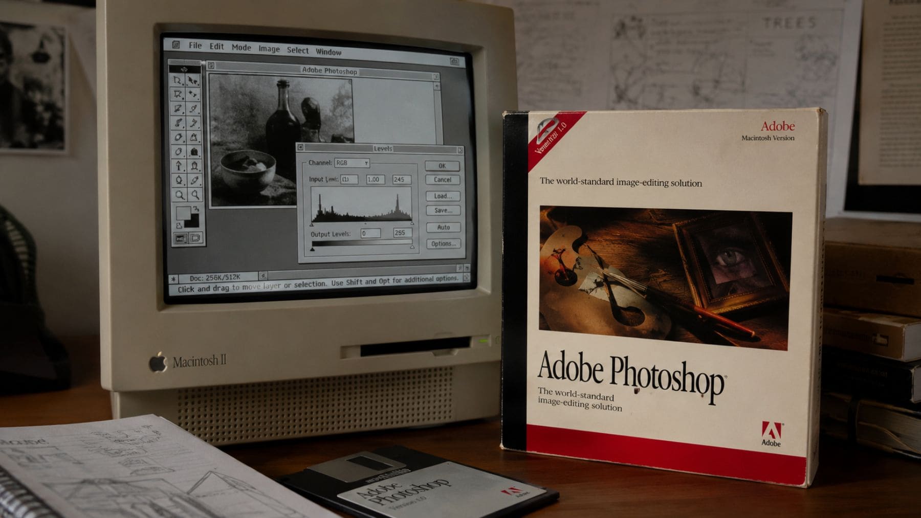 Primeras versiones de Photoshop en un Macintosh clásico junto a la caja original del programa de Adobe.